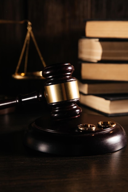 Vertical image of wedding rings on wooden mallet at table in courtroom