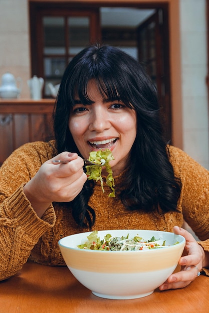 サラダを食べる若いラテン系女性の垂直方向の画像