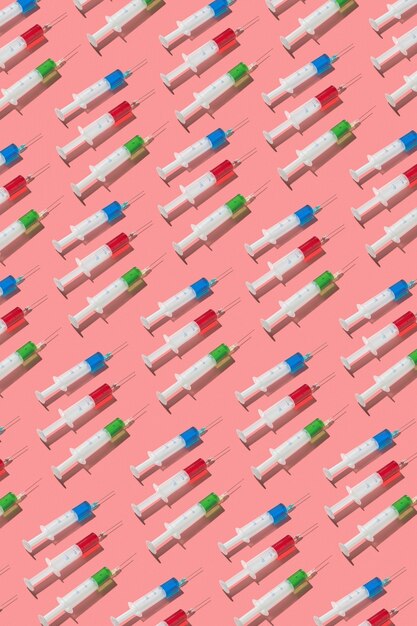 Vertical medical pattern from surgical disposable syringes with red, green and blue serum or drugs for injections