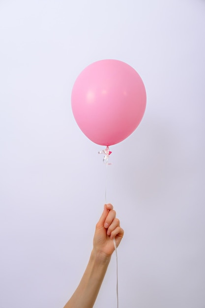 Vertical one minimal pink balloon in hand on white background copy space element of decorations for birthday party wedding festival