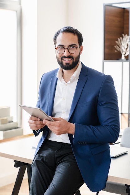 Vertical photo of Arabian businessman teacher lecturer freelancer boss conducting lesson online using digital tablet checking sending emails elearning working remotely on lockdown