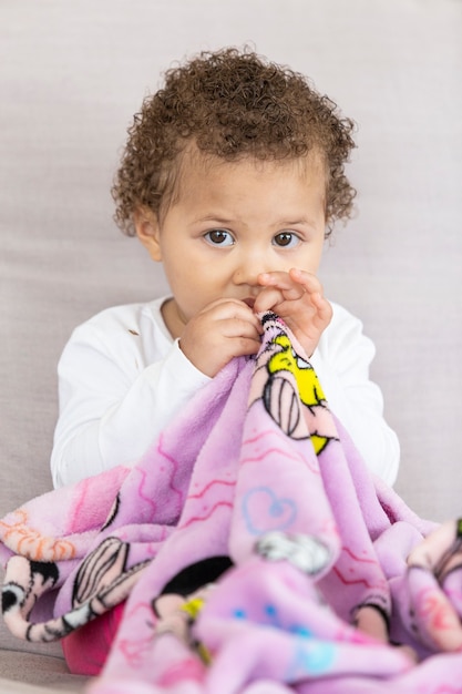 Vertical photo of baby holding covered sitting.