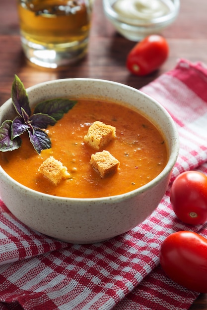 Вертикальная фотография чаши томатного супа с базиликом и сухими тостами