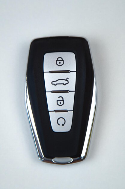 Vertical photo the car key is black with a metallic color with buttons for opening the trunk door