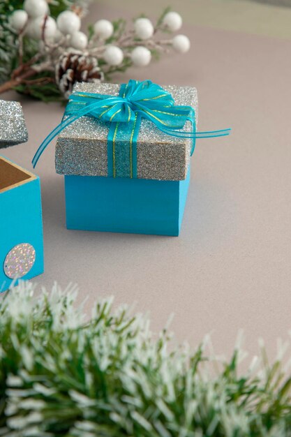 Vertical photo of Christmas background with a silver gift with blue bow and green garland.