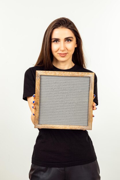 Vertical photo of cute lady holding board and looking at the camera