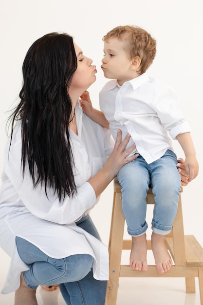 Vertical photo of darkhaired mom and barefoot son sending aerial kisses to each other boy standing o