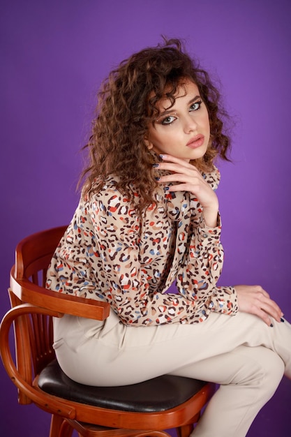 Vertical photo fo young lady sittin on a chair on purple background High quality photo