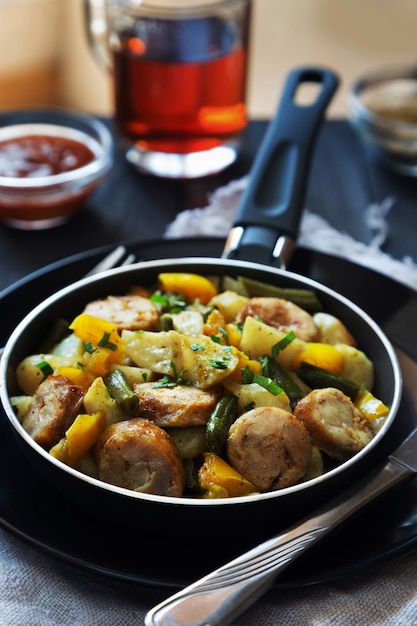 Vertical photo of fried potatoes with sausages