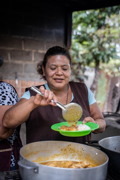 Foto foto verticale di una donna generosa che serve cibo in una cucina rurale all'aperto