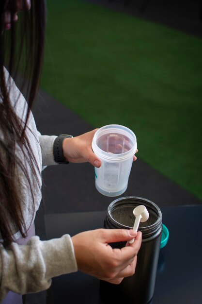 Photo vertical photo of the hands of an athlete who is preparing protein after training