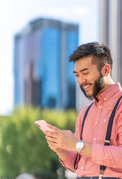 Vertical photo of a happy asian businessman using a mobile