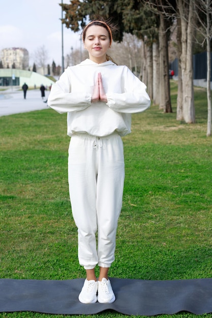 手をつないで公園で瞑想をしている若いアスリートの縦の写真高品質の写真