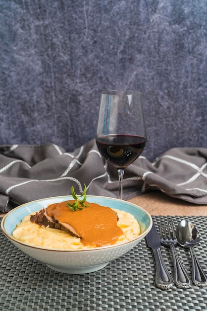 Вертикальное фото тарелки с кукурузным крахмалом и жареной говядиной, подаваемой с вином