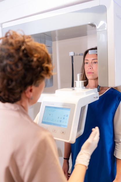 Vertical photo of the rear view of a dentist using a x ray dental machine with a patient