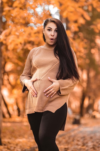 Vertical photo shocked surprised amazed pregnant woman sitting on the bench in autumn city park