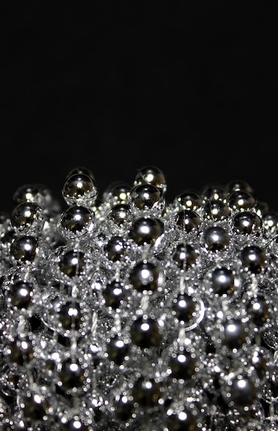 Vertical Photo Of Small Glittering Beads In A Bunch Over Black Background