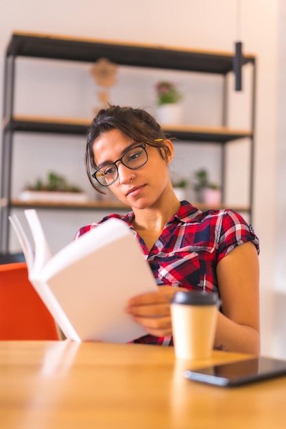 Foto foto verticale di una scena tranquilla di una donna che legge un libro a casa