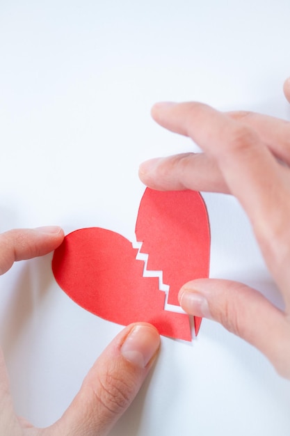 Vertical photo two hands fixing a broken heart on white background with copy space