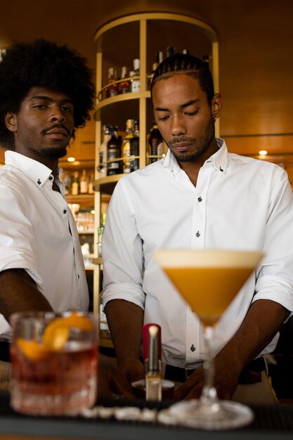 Vertical photo of two latin bartenders making cocktails