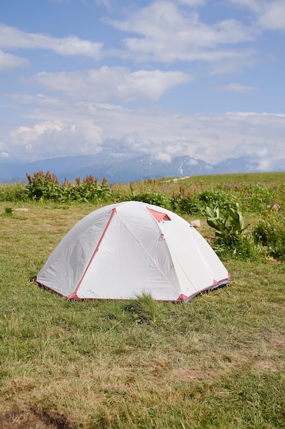 Foto foto verticale di una tenda turistica bianca sullo sfondo delle montagne