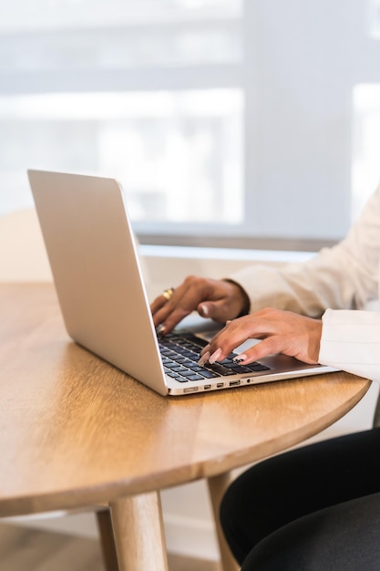 Vertical photo with closeup of a businesswoman's hands working on laptop at wooden table