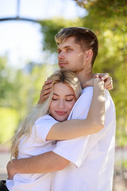 Vertical photo of a young beautiful couple hugging each others at the park High quality photo