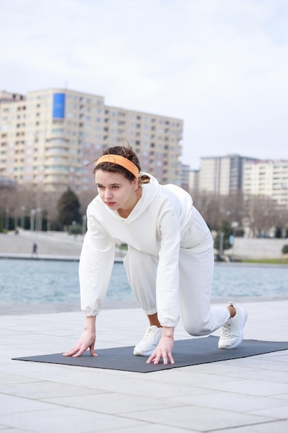 Vertical photo of young lady stand on yoga mat at the park High quality photo