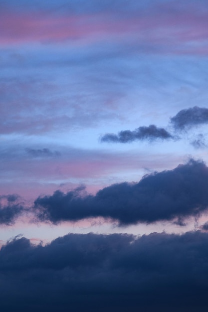 사진 구름이 가득한 날씨에서 해가 지는 파란 구름의 수직 사진 미학적 중립 사진 만적 인 하늘