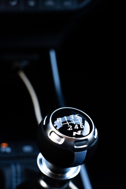Vertical photography of the manual gearshift lever of a luxury\
car with dark interior