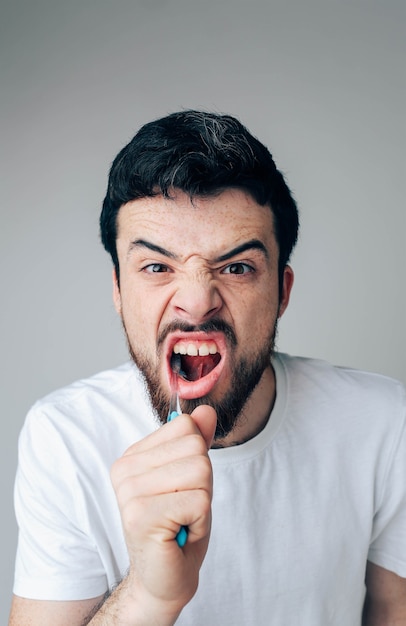 Vertical picture of handsome bearded guy cleaning teeth. Using toothbrush with toothpaste. Oran and dental care. Close up