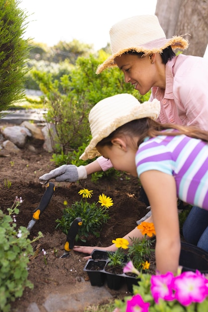 Vertical pictures of caucasian mother and daughter spending time together in the garden planting. Family time spending outside , garden, gardening, concept.