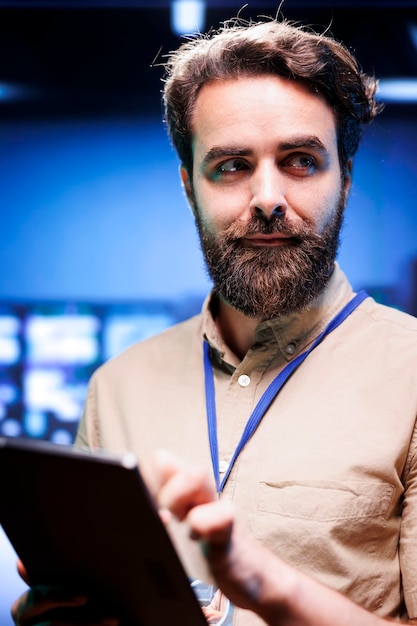 Vertical portrait of admin in cloud computing business with server racks used for computationally intensive tasks such as 3D rendering. Manager using tablet for yearly equipment inspection, close up