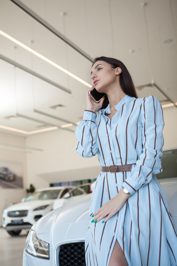 Photo 自動車販売店で彼女の携帯電話で話しているエレガントな女性の縦の肖像画