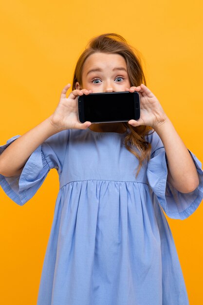 Vertical portrait of a girl with a phone in a horizontal position with a layout on yellow