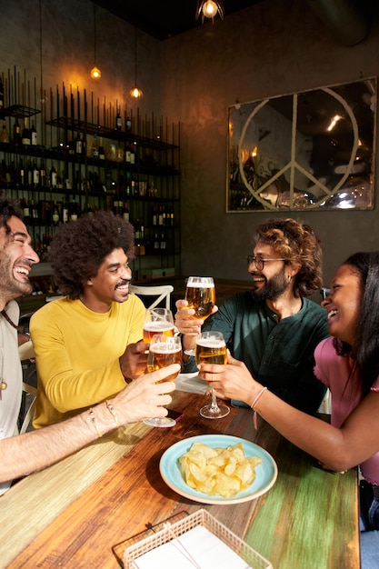 직장 후 술집 해피 아워에서 맥주를 마시며 토스트하는 동료 노동자 그룹의 수직 초상화