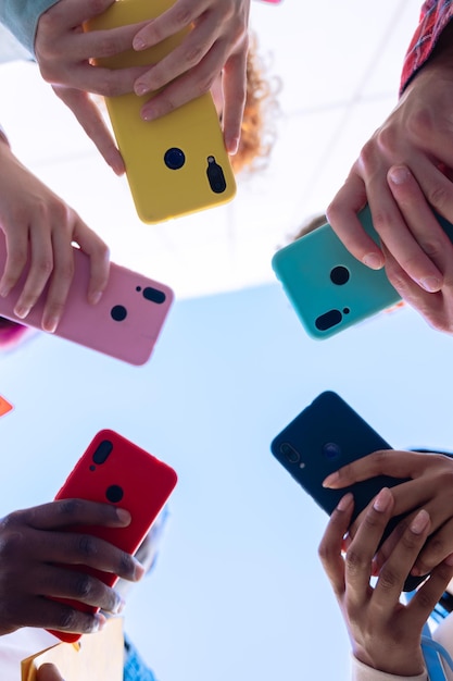 vertical portrait group of people holding colorful smartphones in a circle