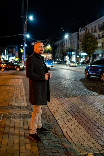 Vertical portrait of a handsome bearded mature man Evening street with yellow lights Urban style