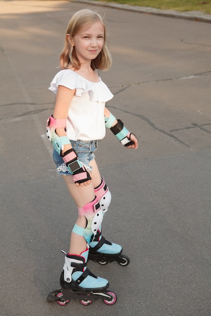 Vertical portrait of a happy young girl smiling while rollerblading