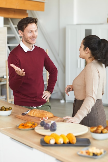 友人と屋内でディナーパーティー中にチャットする大人の男性と女性の縦の肖像画