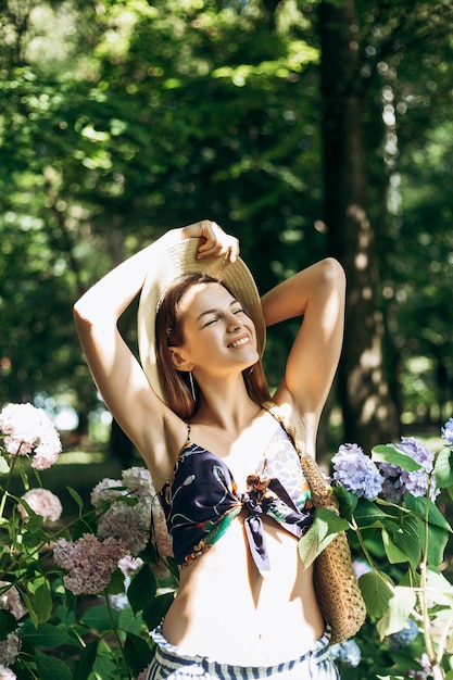 Фото Вертикальный портрет красивой молодой женщины, позирующей в парке с цветущими гортензиями