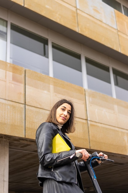 Vertical portrait of a smiling businesswoman with an electric scooter