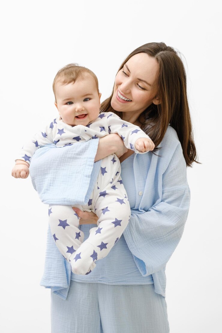 Vertical portrait of smiling mother and baby child woman in blue clothes holding baby in her arms on white background