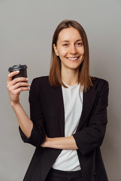 Vertical portrait of a smiling woman taking a break and enjoying a coffee