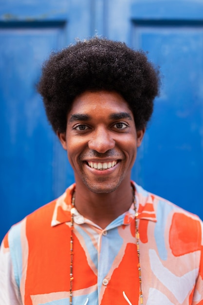 Vertical portrait of smiling young african american man with afro hairstyle looking at camera