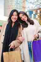 Photo vertical portrait of two multiracial women carryng shopping bags and smiling looking at camera a