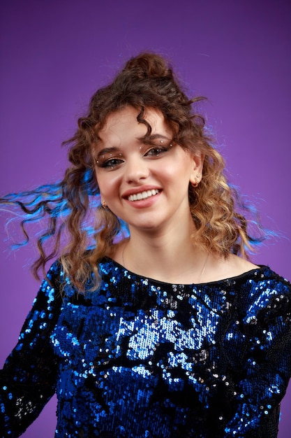 A vertical portrait of a young curlyhaired girl stretching her hair and laughing High quality photo