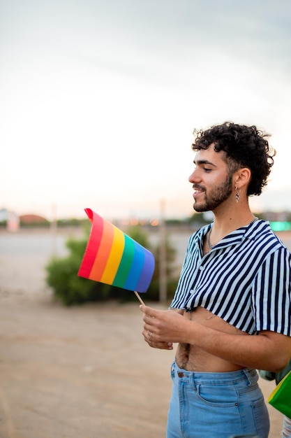 Vertical portrait of young gay man holding rainbow lgbt flag Copy space LGBT rights and tolerance concept