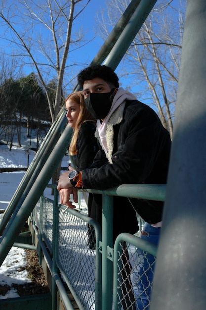 Vertical portrait of a young interracial tourist couple with protective mask on a romantic trip