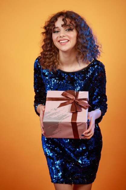 Vertical portrait of young lady holding present box and smiling High quality photo